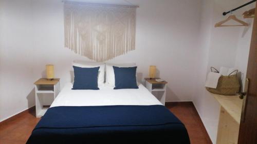 a bedroom with a large bed with blue pillows at Casa da Pedra in Pedrógão