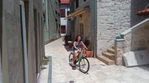 een vrouw die op een fiets door een steegje rijdt bij Apartman Belamaric in Šibenik