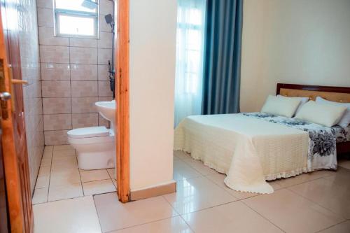 een slaapkamer met een bed en een douche en een toilet bij Le Ptit Zinc in Kigali