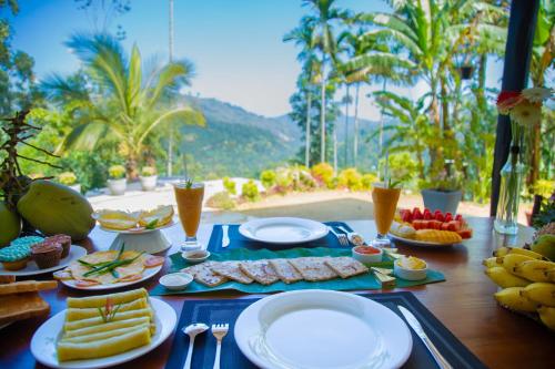 a table with plates of food and drinks on it at Tunnel Top Inn Ella in Ella