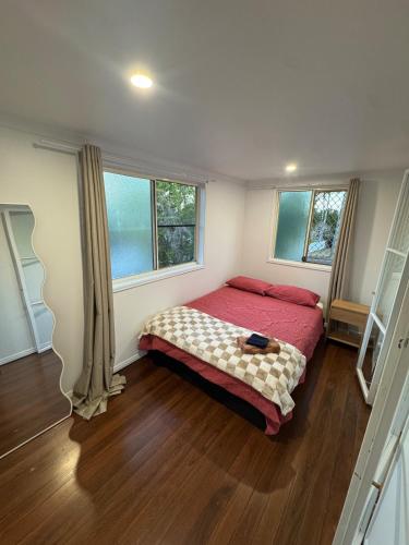 1 Schlafzimmer mit einem roten Bett und 2 Fenstern in der Unterkunft 2 Bedroom Beauty, The Range in The Range