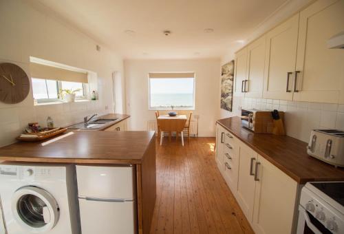 a kitchen with white cabinets and a table with a window at Marine Villa By Air Premier in Saltdean