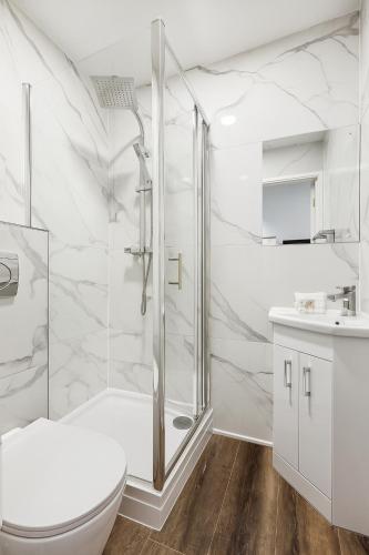 a white bathroom with a shower and a toilet at The Little Venice Studios in London