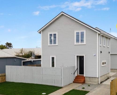 a white house with a white fence at Modern Heritage 2BR Home in Christchurch