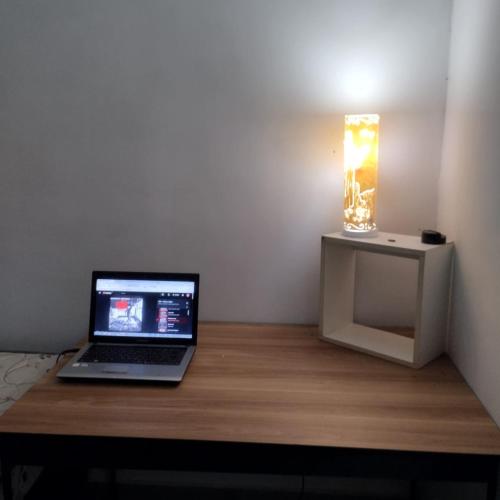 un ordinateur portable posé sur un bureau en bois avec une lampe dans l'établissement Estúdio Vênus, à Alto Paraíso de Goiás