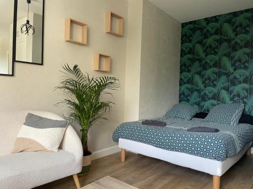 ein Schlafzimmer mit einem Bett und einem Sofa und einer Pflanze in der Unterkunft Le P’tit B - Quartier Saint-Michel/Centre Ville in Saint-Brieuc