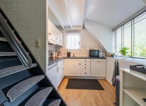 a large kitchen with white cabinets and a staircase at Boshuisje Rekem Charly in Lanaken