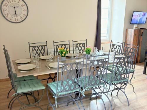 a dining room table with chairs and a clock on the wall at Les Glaneuses gîte Entre Amis centre-bourg à 3 min du Puy duFou in Les Épesses