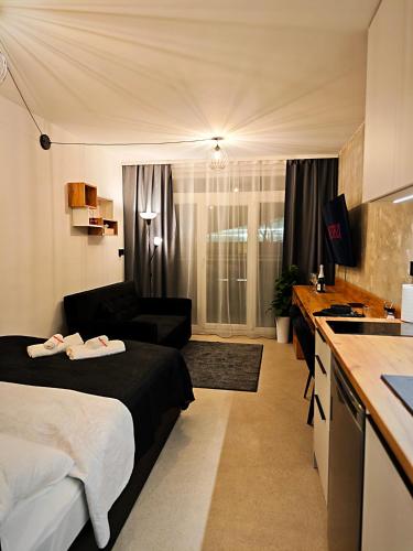 a bedroom with a bed and a kitchen with a couch at Axiom Suites - Zenith II - Netflix, HBO, Champagne in Košice