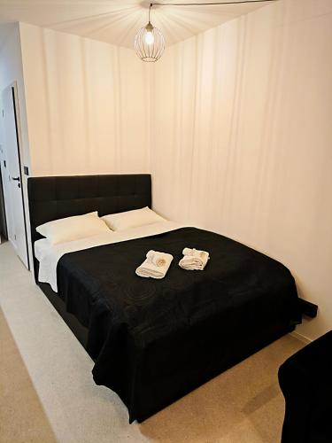 a bedroom with a black bed with two towels on it at Axiom Suites - Zenith II - Netflix, HBO, Champagne in Košice