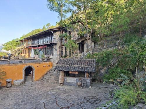 una casa antigua con un edificio en la ladera de una colina en Villa Thẩm mã, en Dồng Văn