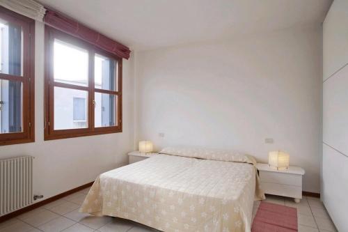 een witte slaapkamer met een bed en een raam bij Locappart Giudecca in Venetië
