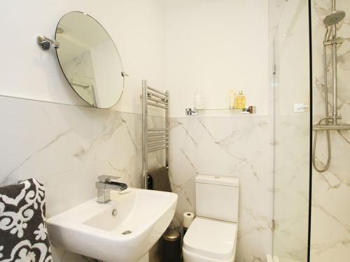 a bathroom with a sink and a toilet and a mirror at Tri Raglan Bach in Beaumaris