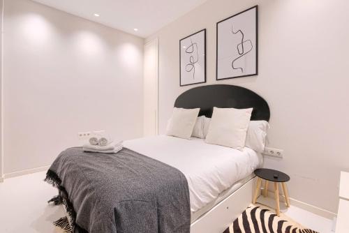 a white bedroom with a bed with a black headboard at Apartamento Bilbo in Bilbao