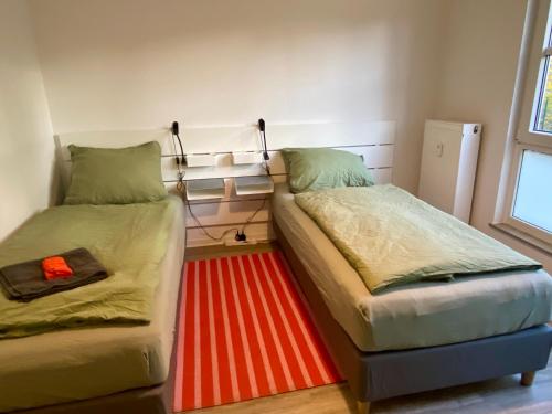 two beds in a room with a red rug at Work&Travel WE13 - Parkplatz, Netflix, Internet für 2 Gäste in Markranstädt