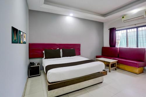 een slaapkamer met een bed en een paarse bank bij Super Collection O Paithan Gate Formerly Rajlaxmi Executive in Aurangabad