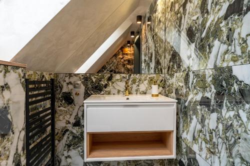 La salle de bains est pourvue d'un lavabo et d'un mur en mosaïque. dans l'établissement Willa Bukowy Las - Everslow, à Szklarska Poręba