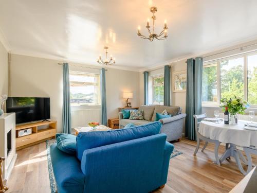 a living room with blue furniture and a tv at Paddock End in Great Plumstead