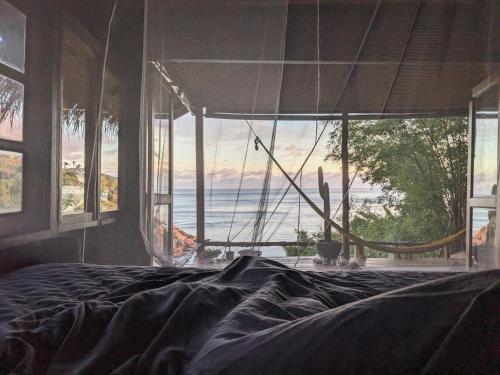 a bedroom with a bed and a view of the ocean at Why Nam Stunning Beach & Ocean View Jungle Penthouse in Ko Phangan