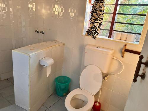 a bathroom with a toilet and a window at Lennana Escape in Ukunda