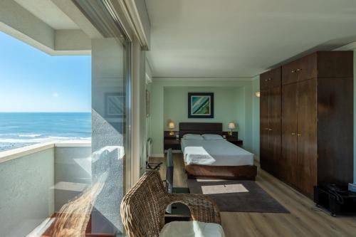 a bedroom with a bed and a balcony with the ocean at Hotel Apartamento Solverde in Espinho