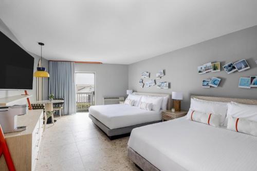 a hotel room with two beds and a flat screen tv at Blue Water Resort in South Yarmouth