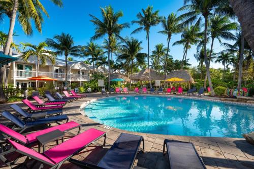 a swimming pool with lounge chairs and palm trees at Havana Cabana at Key West in Key West