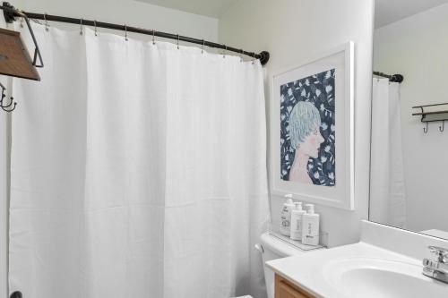 a white bathroom with a shower curtain and a sink at The Clover Cottage in Normaltown in Athens