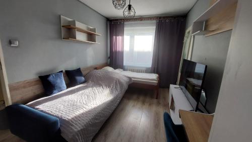 een kleine kamer met een bed en een televisie bij MagMar Studio Byczyna in Byczyna