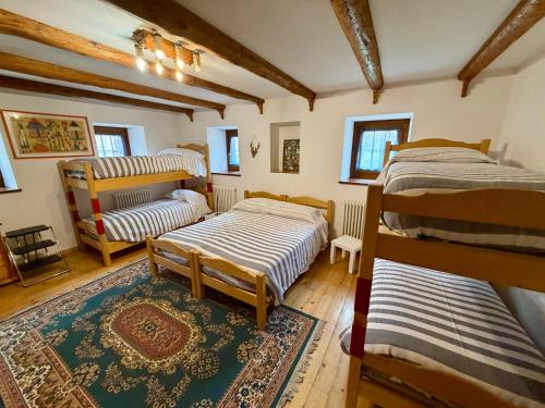 een kamer met drie bedden en een tapijt bij AGRITURISMO FARE BIO in Tarvisio