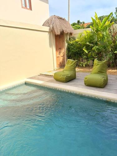 a pool with green pillows next to a house at Villa Saraswati I in Uluwatu