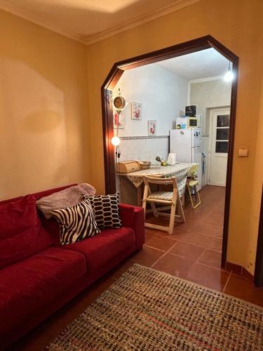 een woonkamer met een rode bank en een tafel bij Casinha de chocolate in Outeiro