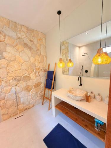 a bathroom with a stone wall and a desk and a mirror at Villa Saraswati I in Uluwatu