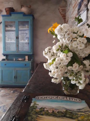 Un jarrón con flores sobre una mesa con un armario azul en Borgofortino, en Rovitolo