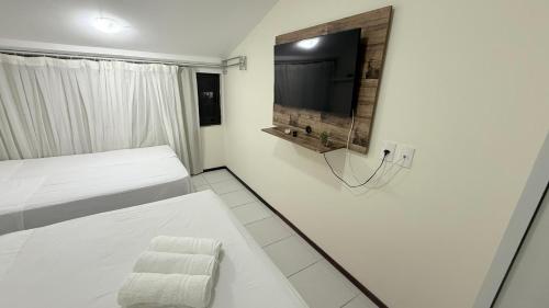 een witte kamer met een bed en een flatscreen-tv bij Muro Alto - Nannai Residence in Porto De Galinhas