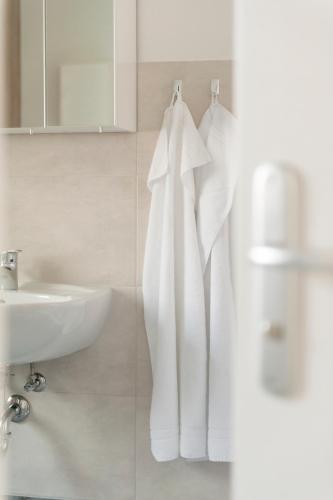 a white bathroom with a sink and a towel rack at Seepark Wolfswinkel in Storkow