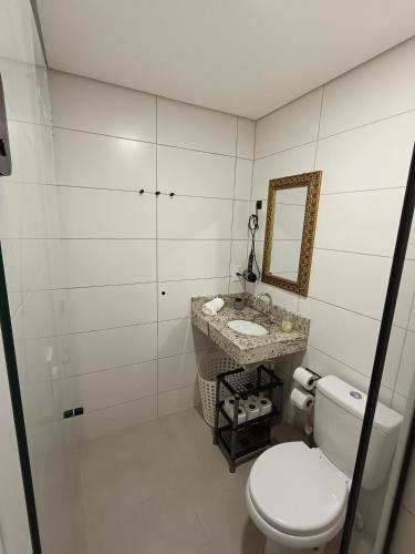 a bathroom with a toilet and a sink and a mirror at Apartamento Home Club, com dois quartos! in Foz do Iguaçu