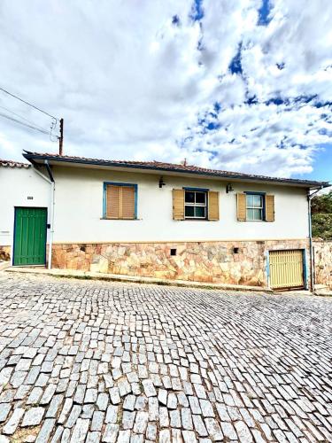a white house with a green door and a brick driveway at Casa Charmosa no Centro Histórico in Ouro Preto
