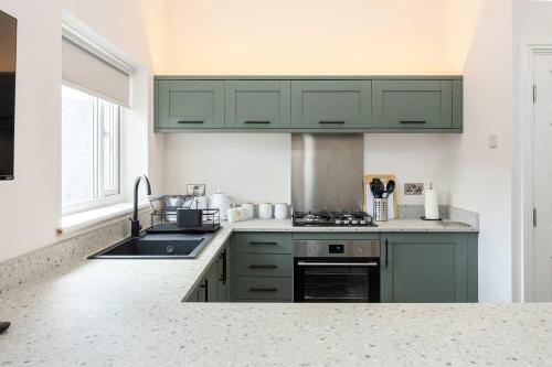 une cuisine avec des armoires vertes et un évier dans l'établissement The Groves Room 3 First Floor, à Manchester