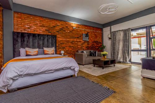 een slaapkamer met een bed en een bakstenen muur bij Maboneng Black Diamond Oasis on Craftmanship Hotel with Wi-fi and Parking in Johannesburg