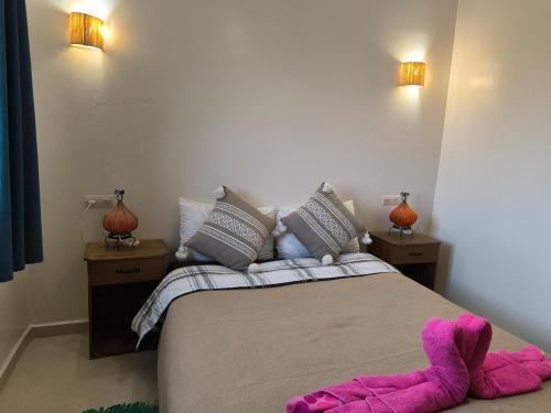 a bedroom with a bed with purple slippers on the floor at Kaouki beachside apartment - 2 people in Essaouira