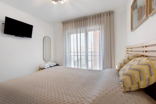 a bedroom with a bed with a television and a window at Coral Beach Oasis in Figueira da Foz