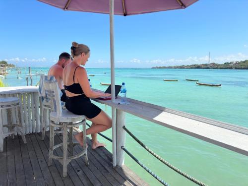 una mujer sentada en una mesa en una terraza con vistas al agua en Rumah Marta Ceningan Island, en Nusa Lembongan