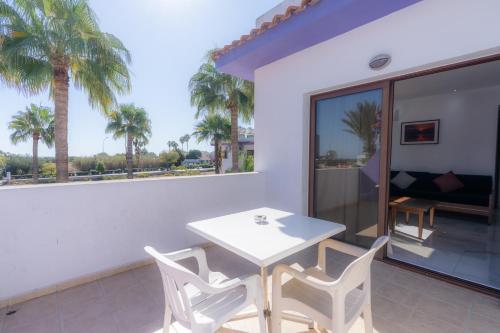a white table and chairs on a balcony with palm trees at Amethyst Napa Annex Apartments in Ayia Napa