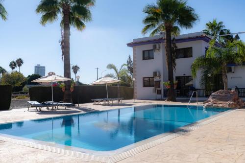 a swimming pool with palm trees and a building at Amethyst Napa Annex Apartments in Ayia Napa