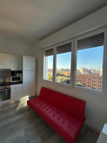 a red couch in a room with two windows at Stayinbologna 3 in Bologna