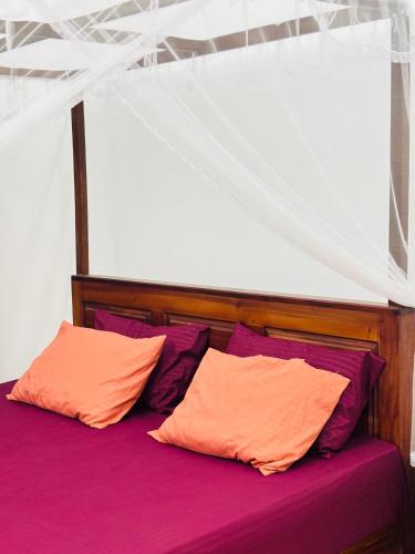 a bed with two orange and purple pillows at The Pearl Heaven in Dickwella