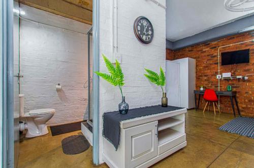 een badkamer met een toilet en een klok aan de muur bij Maboneng Black Diamond Oasis on Craftmanship Hotel with Wi-fi and Parking in Johannesburg