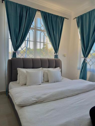 a large bed with blue curtains in a bedroom at SC Luxury Home in Dar es Salaam