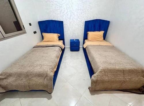 two beds in a small room with blue covers at Sahara luxury suites in Hassilabied